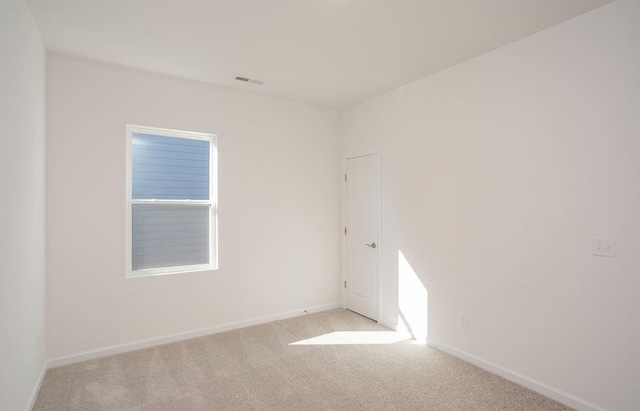 empty room featuring baseboards, visible vents, and light colored carpet