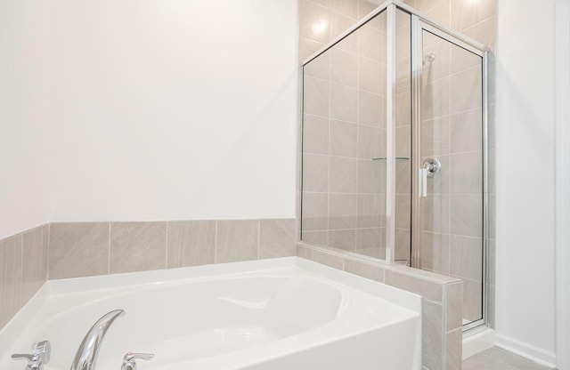 bathroom featuring a stall shower and a bath