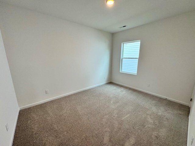 unfurnished room with carpet floors, visible vents, and baseboards