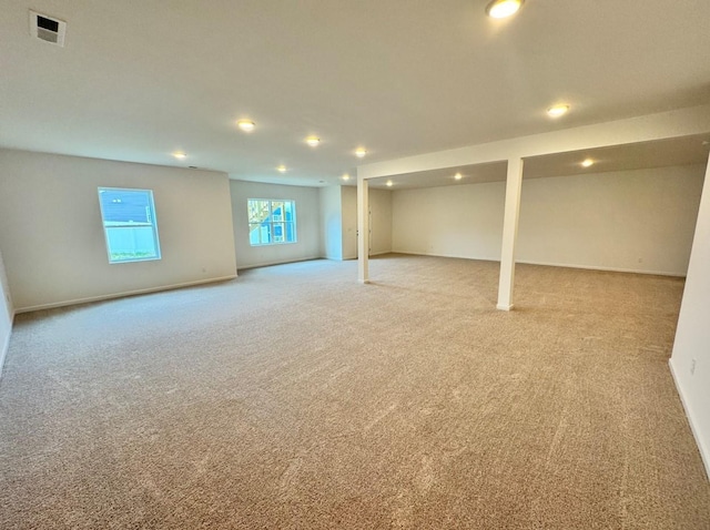 basement featuring light colored carpet, visible vents, and baseboards