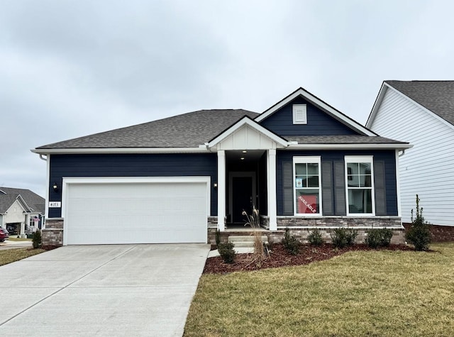 view of front of house featuring driveway, a shingled roof, a garage, and a front yard