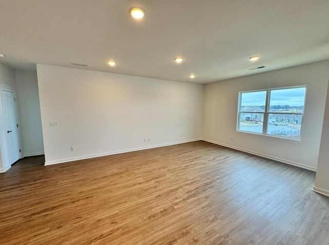 empty room with baseboards, visible vents, wood finished floors, and recessed lighting