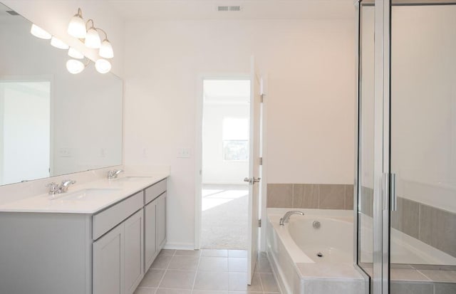 bathroom featuring double vanity, a garden tub, tile patterned flooring, and a sink