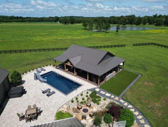 community pool with a water view, an outdoor fire pit, a rural view, and a patio