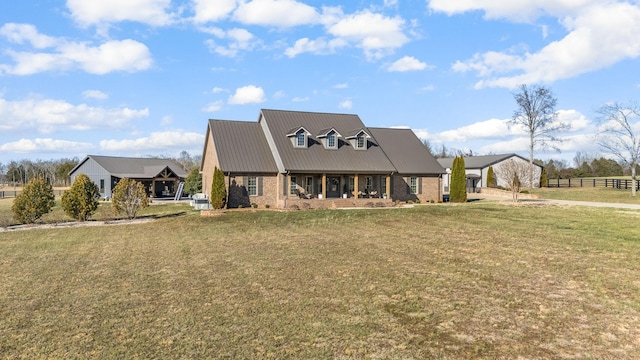 view of front facade with brick siding, metal roof, a front yard, and fence