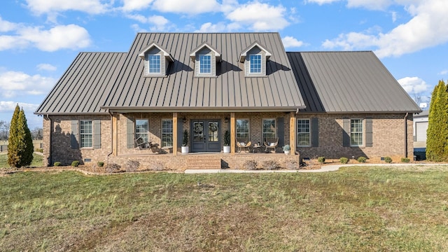 cape cod house featuring a front yard, french doors, crawl space, brick siding, and metal roof