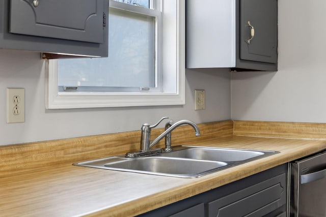 kitchen with gray cabinets, light countertops, dishwasher, and a sink