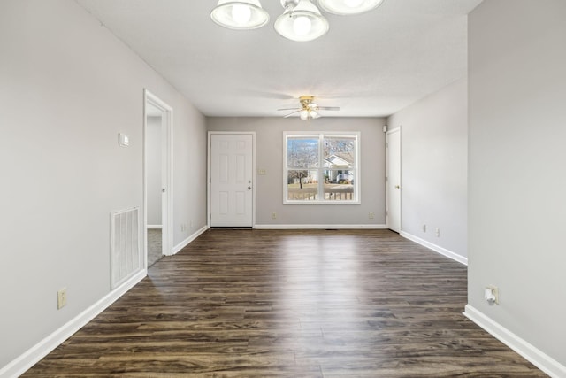 spare room with dark wood-style floors, baseboards, visible vents, and ceiling fan with notable chandelier