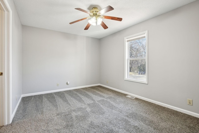 spare room with carpet floors, baseboards, visible vents, and a ceiling fan