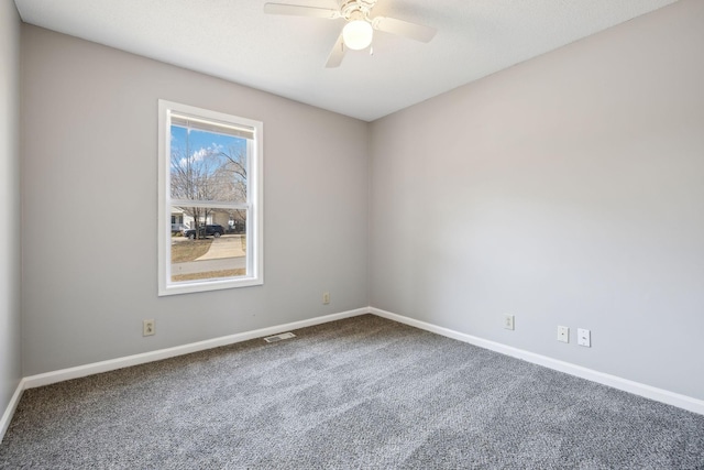 carpeted empty room featuring a ceiling fan, visible vents, and baseboards