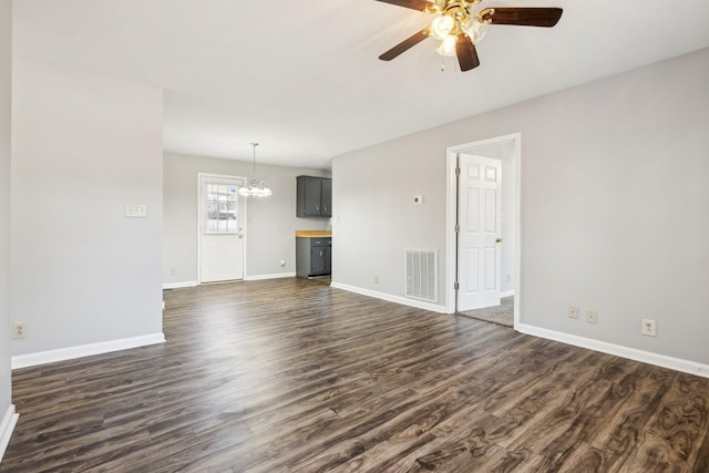 unfurnished living room with baseboards, visible vents, dark wood-type flooring, and ceiling fan with notable chandelier