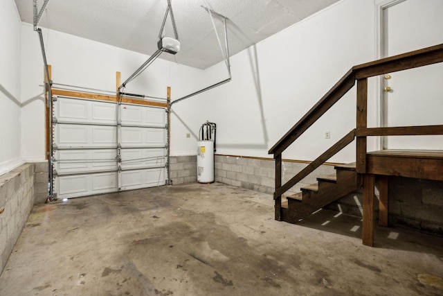 garage featuring a garage door opener, concrete block wall, and electric water heater