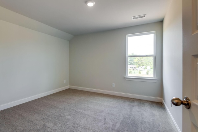 carpeted spare room featuring vaulted ceiling, visible vents, and baseboards