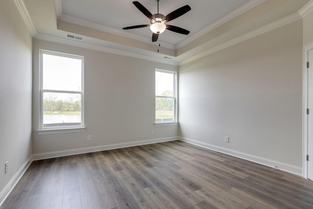 unfurnished room featuring dark wood-style flooring, visible vents, baseboards, ornamental molding, and a tray ceiling