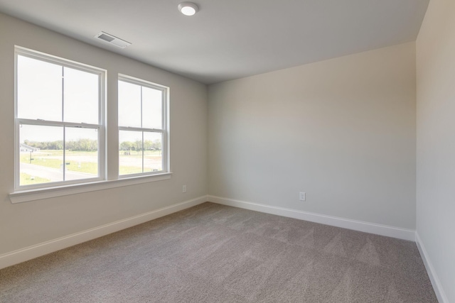 spare room featuring light colored carpet, visible vents, and baseboards