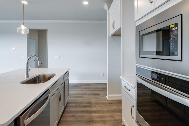 kitchen featuring dark wood-type flooring, stainless steel appliances, crown molding, light countertops, and a sink