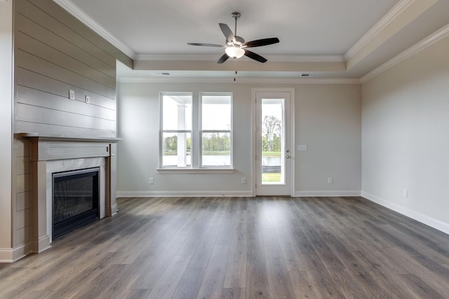 unfurnished living room with crown molding, a tray ceiling, dark wood finished floors, and a premium fireplace