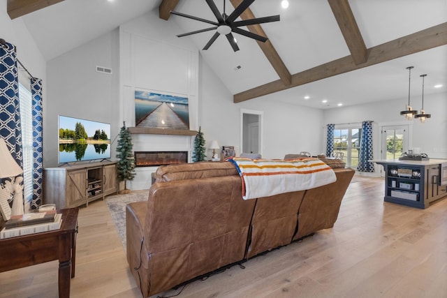 living area featuring light wood-style flooring, beamed ceiling, a fireplace, and visible vents