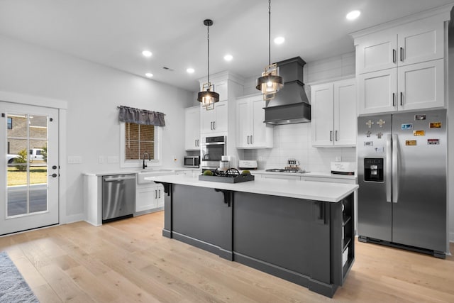 kitchen featuring a kitchen island, light wood-style floors, light countertops, appliances with stainless steel finishes, and custom range hood