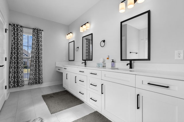 bathroom with double vanity, baseboards, a sink, and tile patterned floors