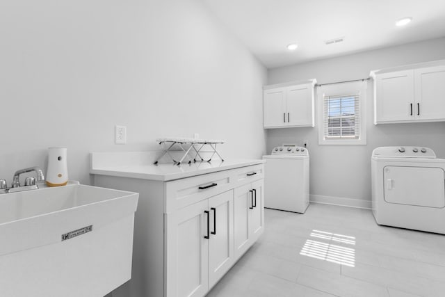 washroom featuring cabinet space, baseboards, visible vents, independent washer and dryer, and a sink