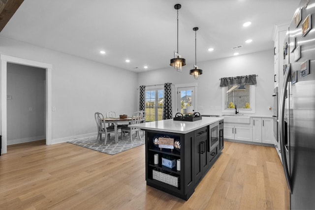 kitchen featuring light countertops, light wood finished floors, open shelves, and white cabinets