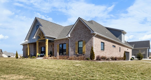 view of front facade with brick siding, a front yard, and a shingled roof