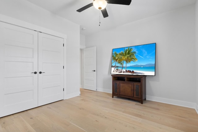 interior space with light wood-type flooring, a ceiling fan, baseboards, and a closet