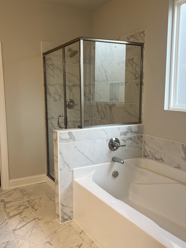 full bathroom featuring a stall shower, baseboards, marble finish floor, and a garden tub