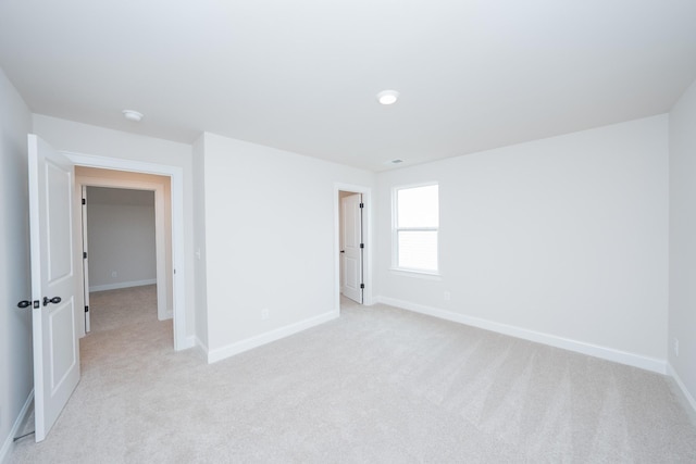 spare room featuring baseboards and light colored carpet