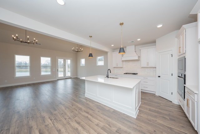 kitchen featuring premium range hood, oven, gas stovetop, a chandelier, and a sink