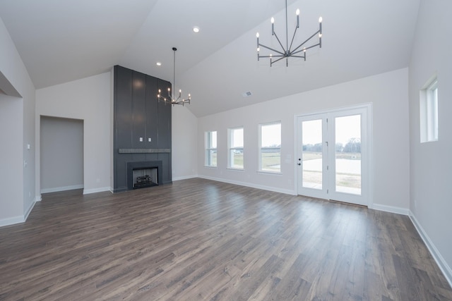 unfurnished living room with high vaulted ceiling, dark wood-style flooring, a fireplace, and a notable chandelier