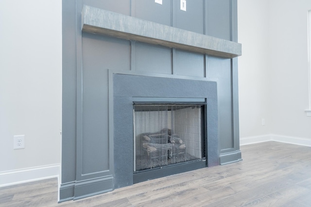 interior details featuring a fireplace, wood finished floors, and baseboards