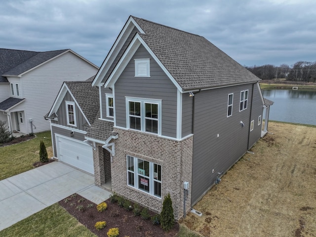 view of front of home with a garage, concrete driveway, roof with shingles, and brick siding