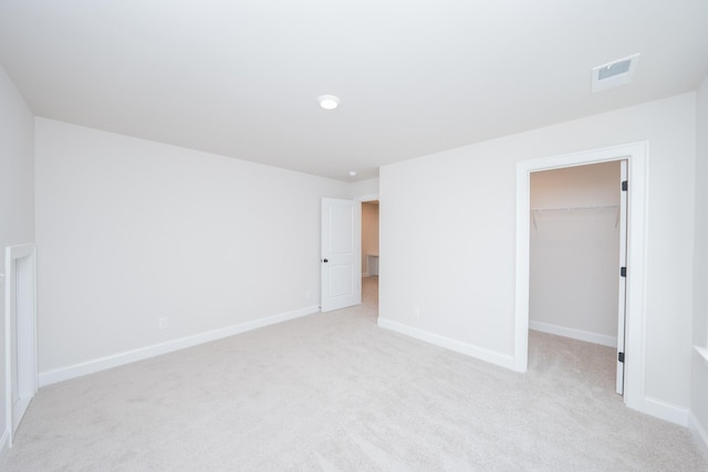 unfurnished bedroom with a spacious closet, baseboards, and light colored carpet