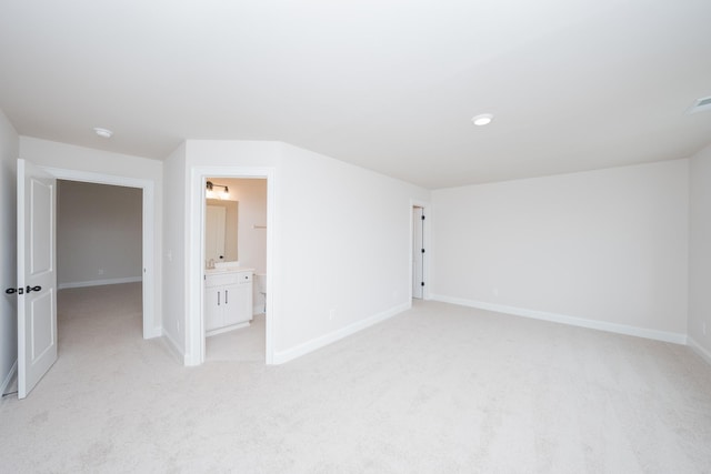 unfurnished bedroom featuring light colored carpet, baseboards, and ensuite bathroom