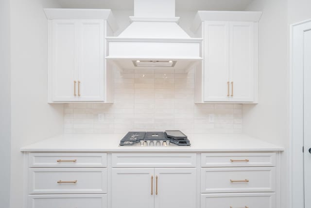 kitchen featuring white cabinets, premium range hood, stainless steel gas cooktop, and light countertops