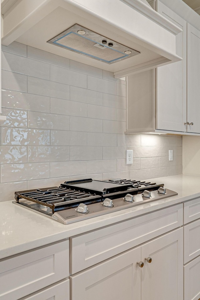 kitchen featuring white cabinets, tasteful backsplash, stainless steel gas cooktop, and light countertops