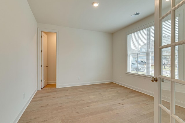 spare room with light wood-style flooring, visible vents, and baseboards