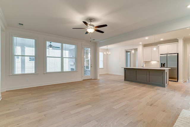 unfurnished living room featuring light wood-style flooring, visible vents, ornamental molding, and a wealth of natural light