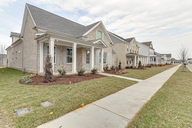 view of front of house featuring covered porch, brick siding, and a front lawn