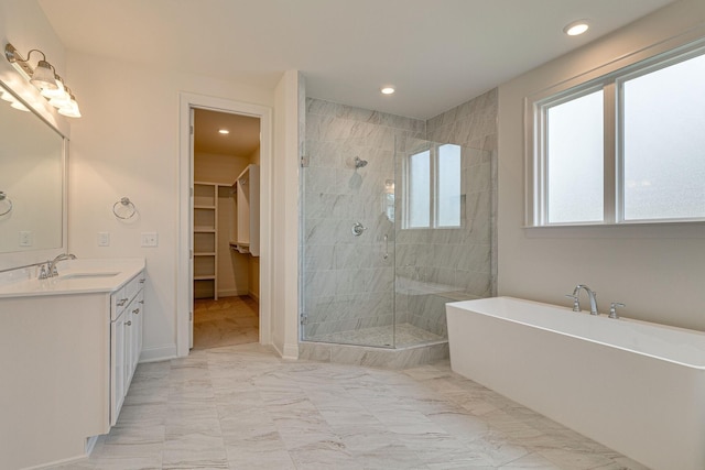 full bathroom with marble finish floor, a soaking tub, a shower stall, and a walk in closet