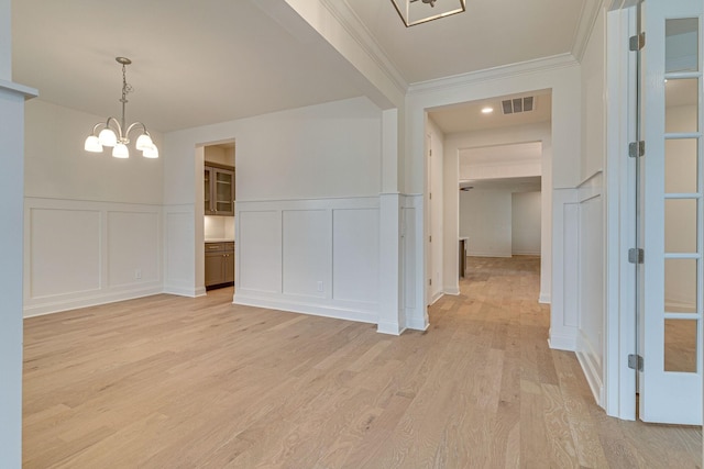 interior space featuring a decorative wall, visible vents, light wood-style floors, an inviting chandelier, and crown molding