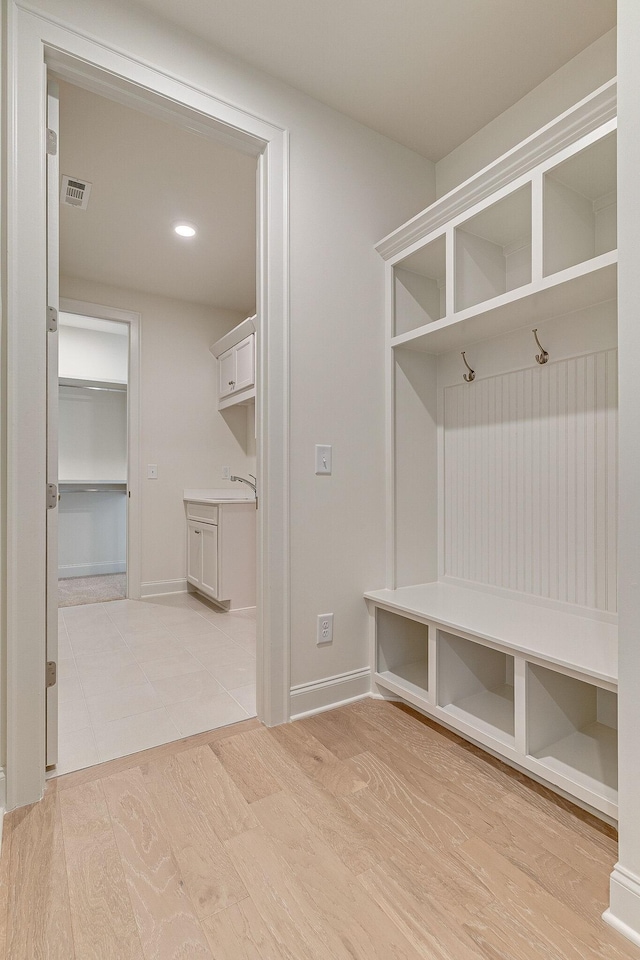 mudroom featuring a sink, light wood-style flooring, visible vents, and baseboards