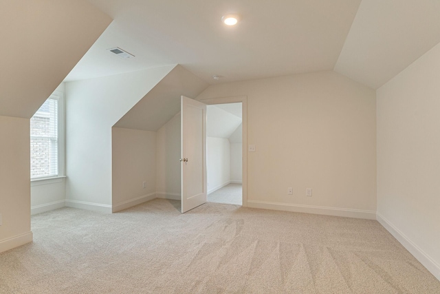 additional living space featuring light carpet, vaulted ceiling, visible vents, and baseboards