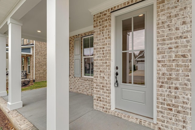 property entrance featuring covered porch and brick siding