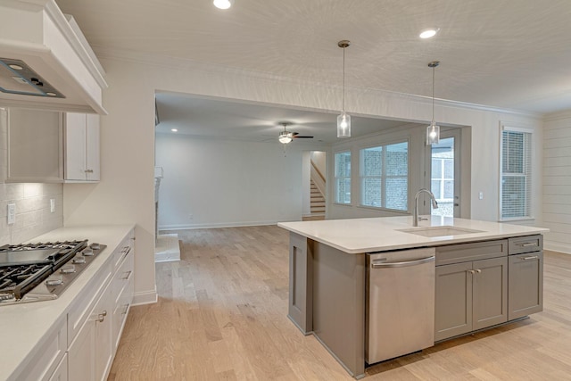 kitchen featuring stainless steel appliances, light wood-type flooring, a sink, and crown molding