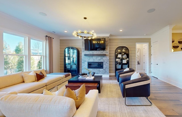 living area featuring a large fireplace, ornamental molding, wood finished floors, and a notable chandelier