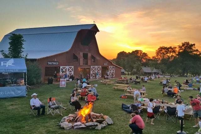 view of home's community with a barn, a fire pit, a lawn, and an outdoor structure