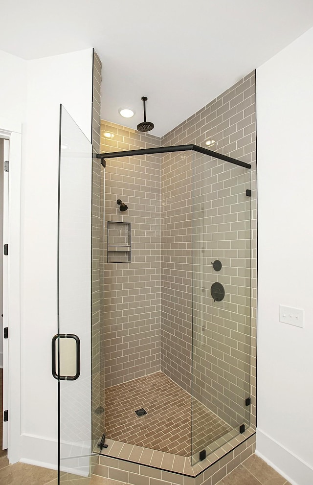 bathroom with a shower stall and baseboards